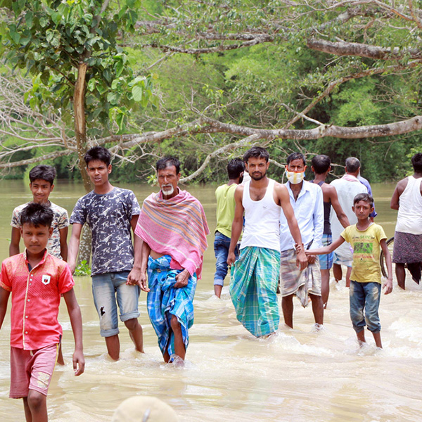 Nagaon, Assam / India - May 30 2020: People wades the flood water submerged road in Assam, India